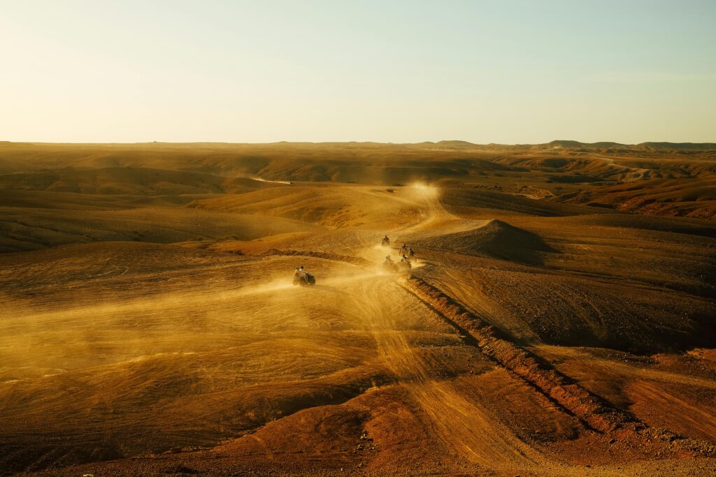 ATVs speed across a vast desert landscape during a stunning sunset, creating a thrilling sense of adventure.